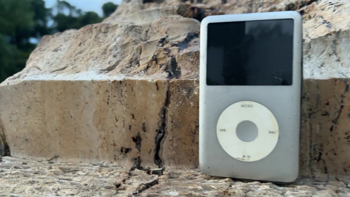 Reproductor de música con audífonos de cable sobre una mesa de madera.