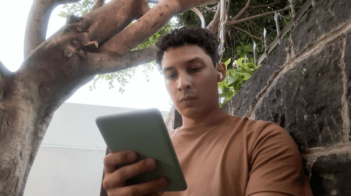 Mario sosteniendo un e-reader con funda verde, al aire libre.